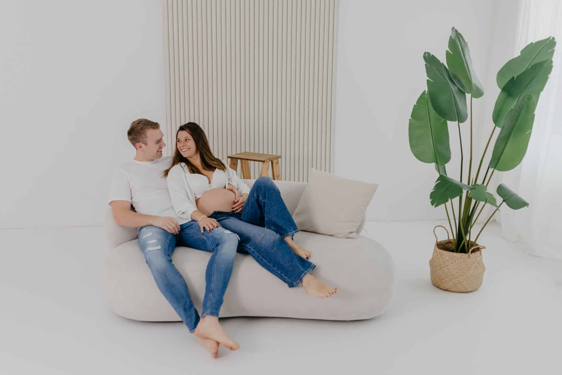 Paar sitzt zusammen auf dem Sofa und freuen sich auf ihr Baby
