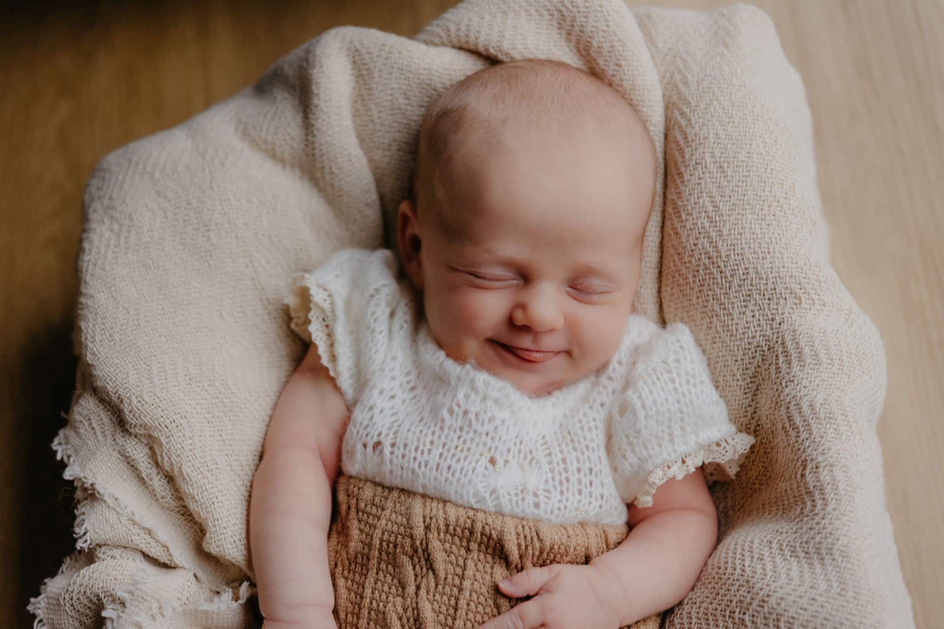 Baby liegt in einem Körbchen und lacht